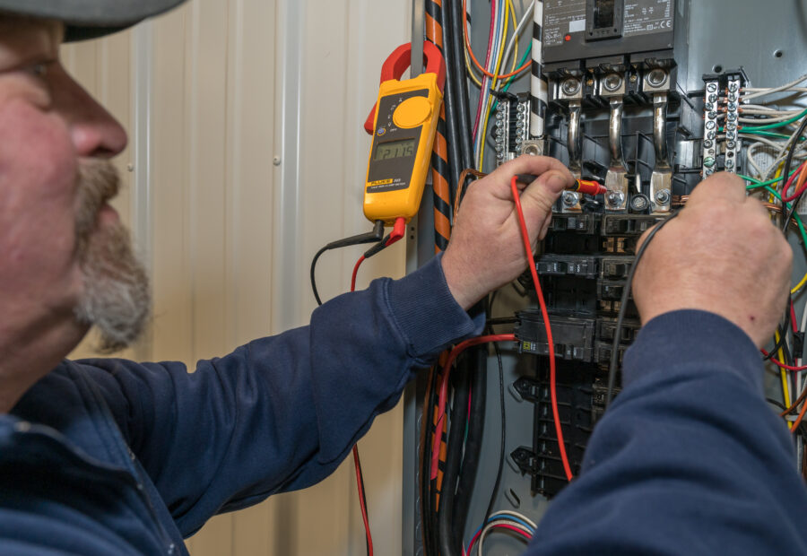 A certified electrician working on a breaker panel